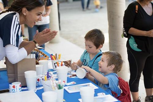 Two children guided by a teacher doing an arts and crafts project to learn more about water